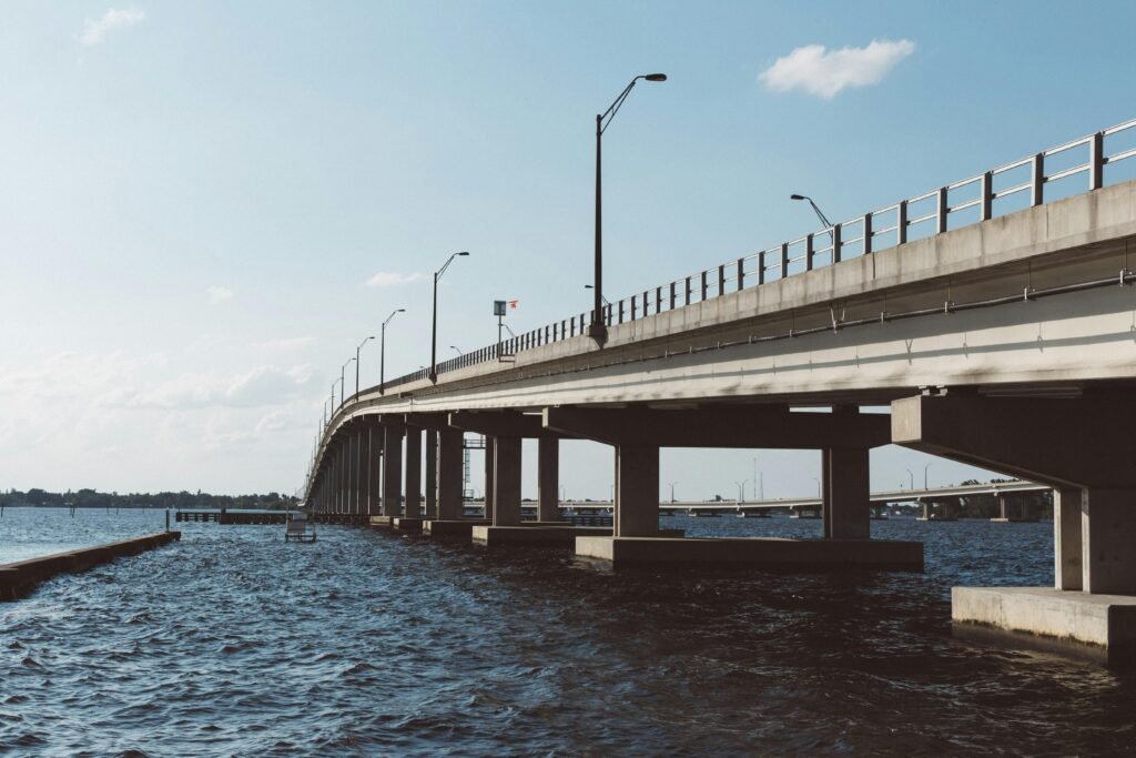 Wide-angle view of a concrete bridge over a river under a clear blue sky, showcasing modern infrastructure.
