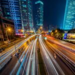 Dynamic long exposure night shot of urban cityscape with vibrant light trails and towering skyscrapers.