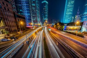 Dynamic long exposure night shot of urban cityscape with vibrant light trails and towering skyscrapers.