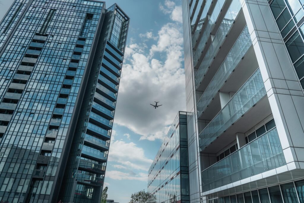 Modern skyscrapers in Poznań with an airplane soaring above on a clear day.
